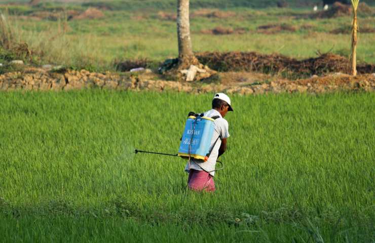 Un agricoltore sparge pesticidi in un campo