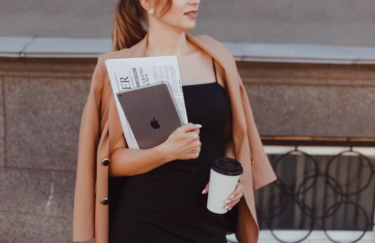 donna con pc e giornale che va al lavoro