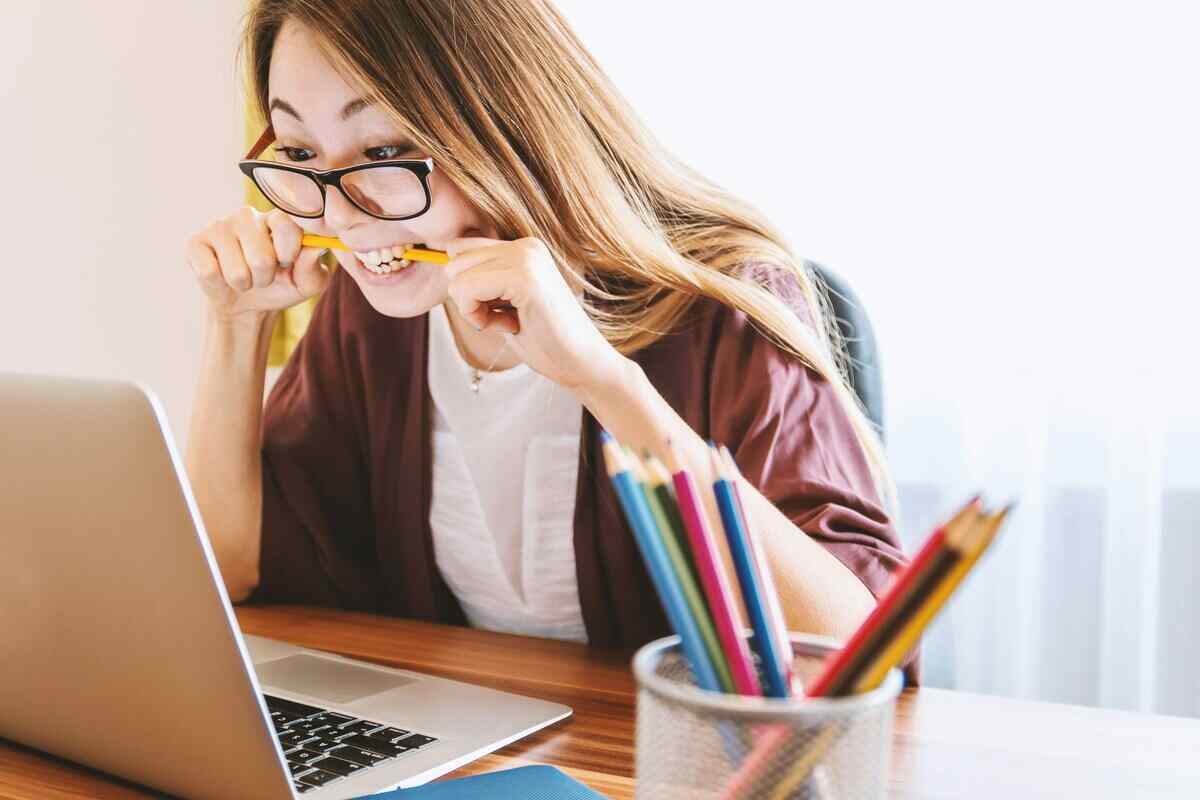 studentessa stressata guarda il pc con matita tra i denti